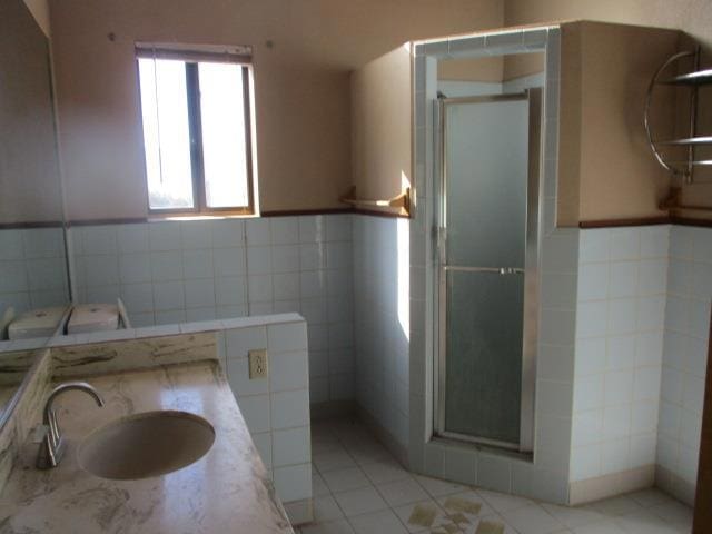 bathroom featuring vanity, tile patterned flooring, tile walls, and walk in shower