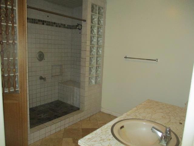 bathroom with tiled shower, vanity, and tile patterned flooring