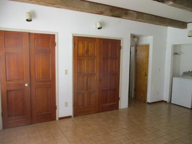 unfurnished bedroom with beamed ceiling and washer / clothes dryer