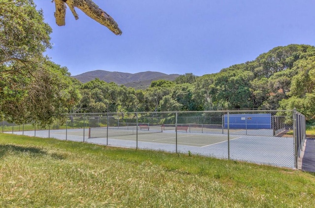 view of tennis court featuring a mountain view and a lawn