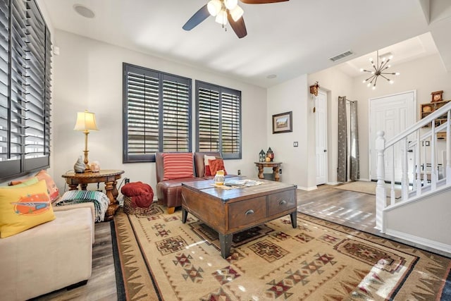 living room featuring ceiling fan with notable chandelier and hardwood / wood-style flooring