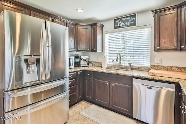 kitchen with sink, light stone counters, stainless steel appliances, and light tile patterned flooring