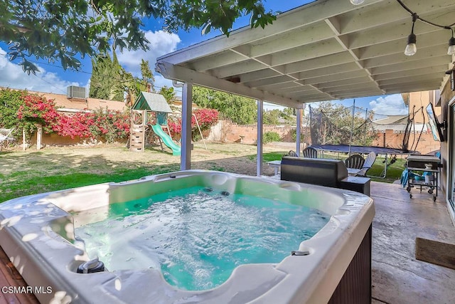 view of patio with a playground, a trampoline, and a hot tub