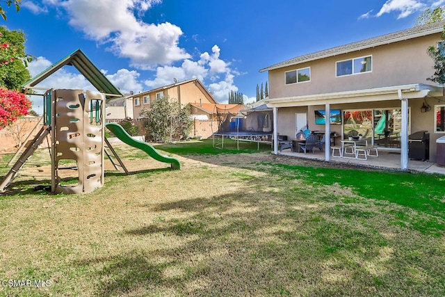 exterior space featuring a trampoline, a yard, and a patio