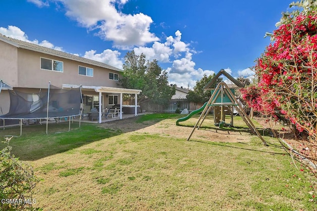 view of yard featuring a trampoline, a patio area, and a playground