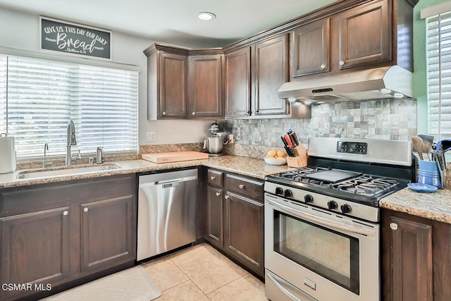 kitchen featuring sink, dark brown cabinetry, light stone countertops, appliances with stainless steel finishes, and light tile patterned floors