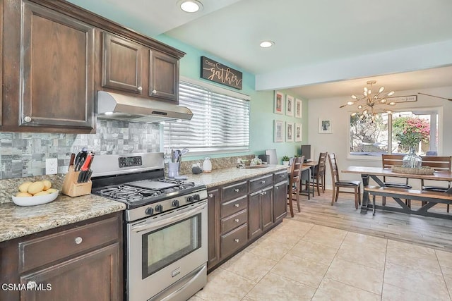 kitchen with decorative backsplash, plenty of natural light, dark brown cabinets, and stainless steel gas range oven