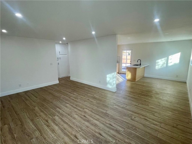 unfurnished living room with hardwood / wood-style flooring and sink