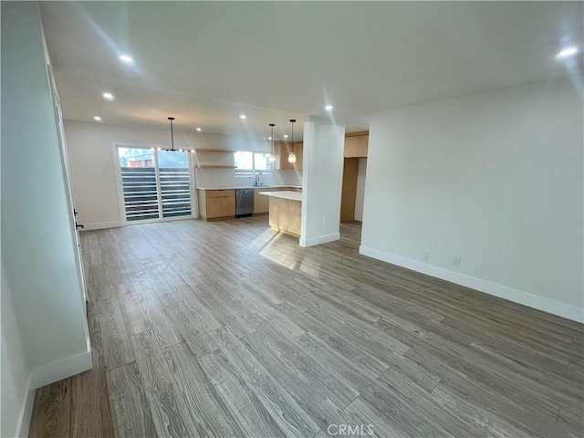 unfurnished living room featuring hardwood / wood-style flooring and sink