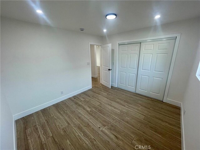 unfurnished bedroom featuring hardwood / wood-style floors and a closet