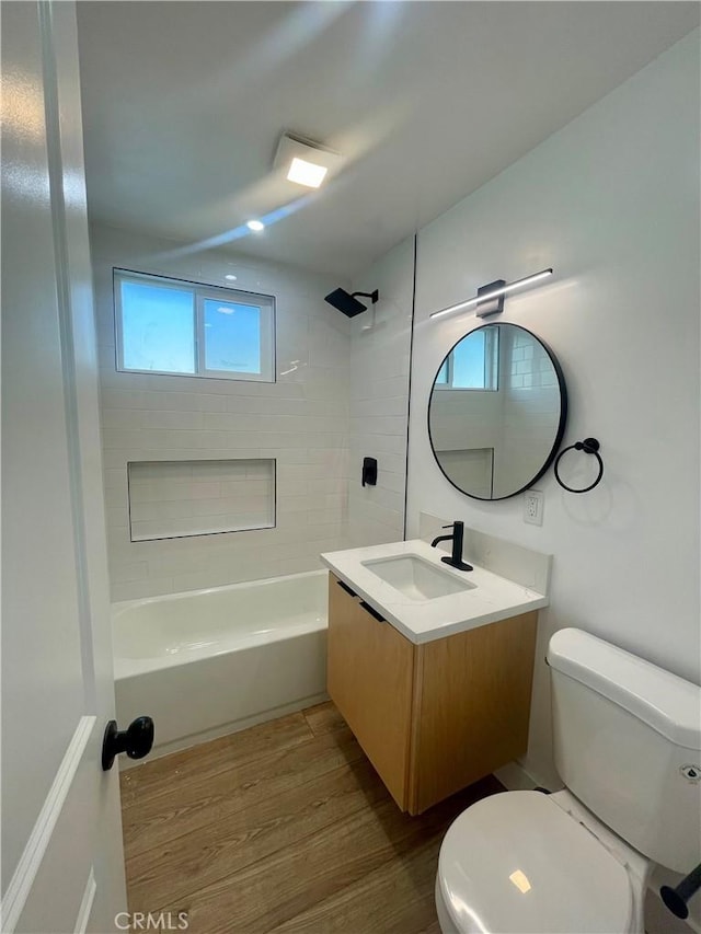 full bathroom featuring hardwood / wood-style floors, toilet, vanity, and tiled shower / bath