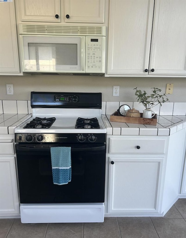 kitchen with white cabinets, gas stove, and tile patterned flooring