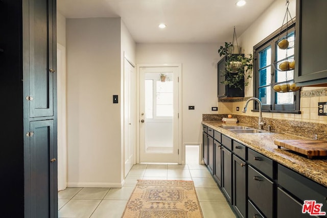 kitchen featuring light stone countertops, sink, decorative backsplash, and light tile patterned floors