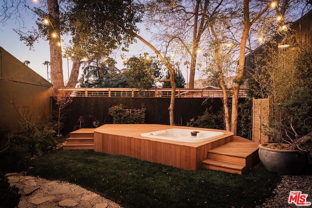 yard at dusk with a wooden deck and an outdoor hot tub