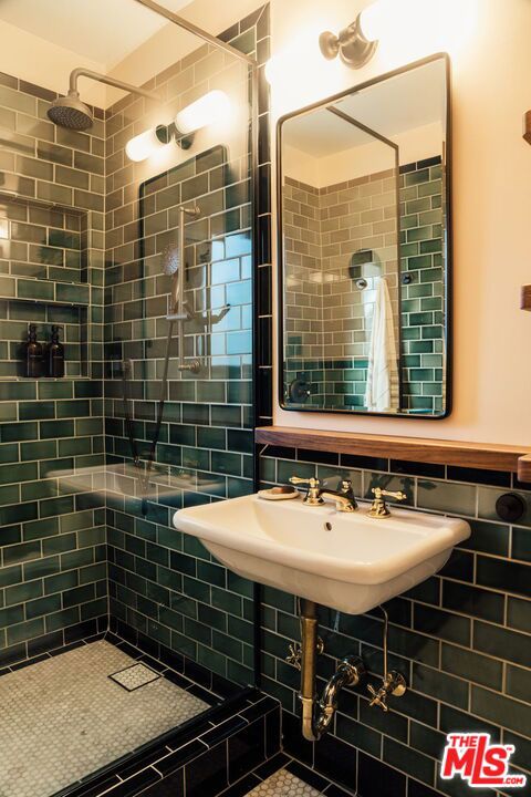 bathroom featuring sink, tile walls, and a tile shower