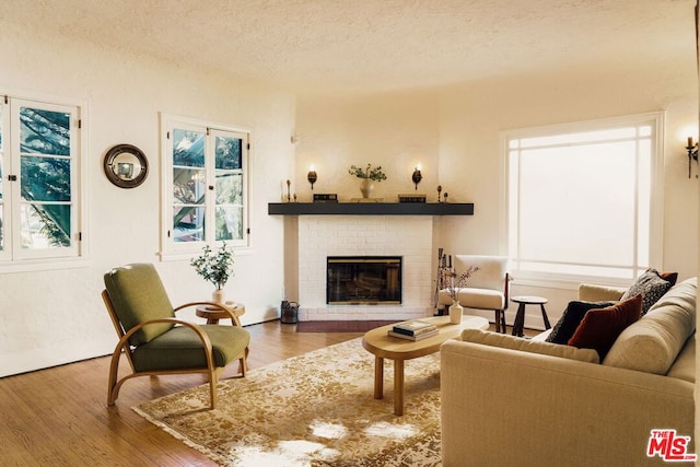 living room featuring a textured ceiling, a brick fireplace, and hardwood / wood-style floors