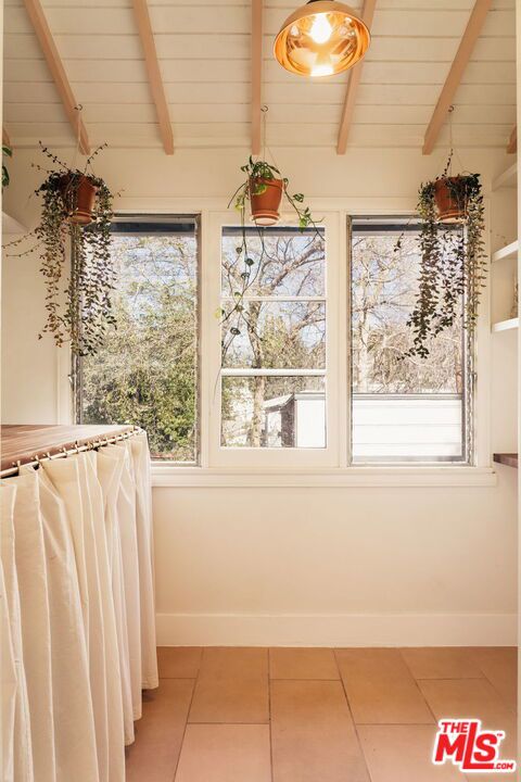 unfurnished sunroom featuring lofted ceiling with beams