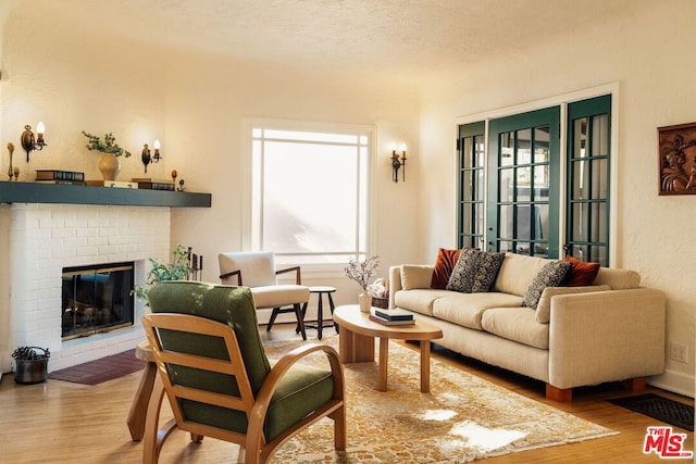 living room featuring wood-type flooring, a fireplace, and a textured ceiling