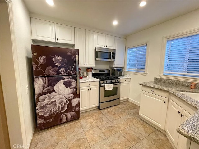 kitchen with light stone countertops, sink, stainless steel appliances, and white cabinetry