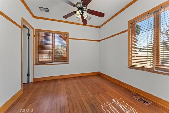 empty room with a healthy amount of sunlight, crown molding, hardwood / wood-style floors, and ceiling fan