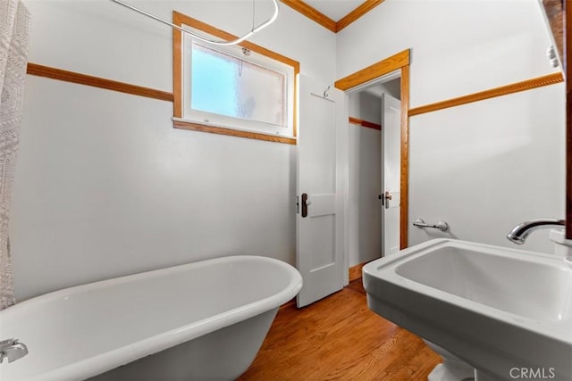 bathroom with sink, hardwood / wood-style floors, a bath, and ornamental molding