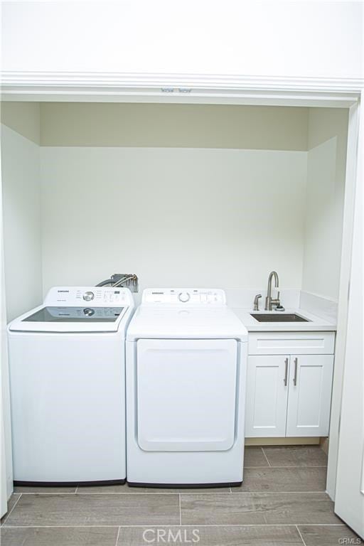 washroom featuring sink, washing machine and clothes dryer, and cabinets