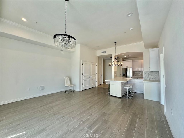 kitchen featuring stainless steel fridge with ice dispenser, a kitchen bar, pendant lighting, white cabinets, and a center island