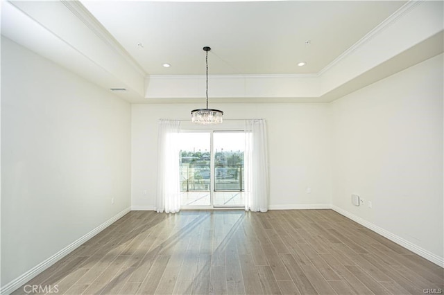 spare room featuring a raised ceiling, crown molding, and hardwood / wood-style flooring