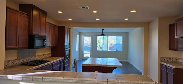 kitchen featuring tasteful backsplash, tile countertops, kitchen peninsula, and black appliances