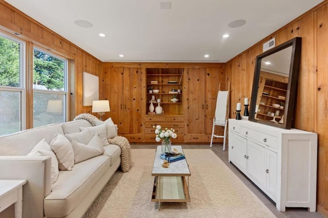 living room with built in shelves, crown molding, and wood walls