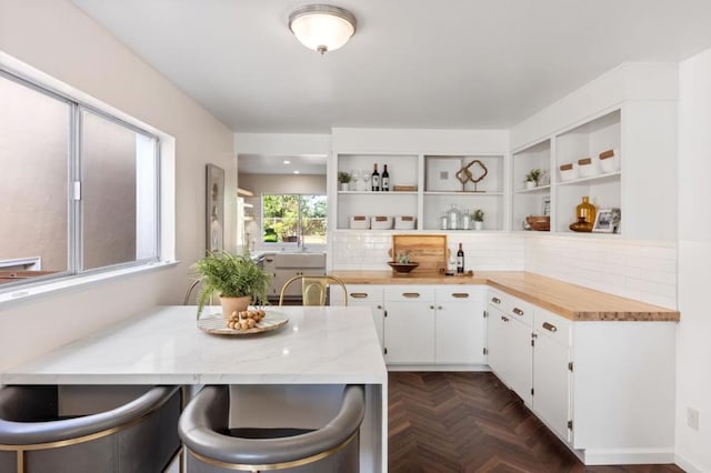 kitchen featuring white cabinetry, dark parquet flooring, butcher block countertops, and kitchen peninsula