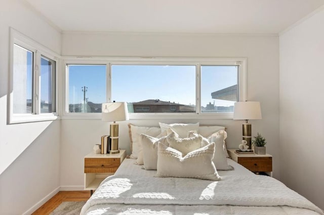 bedroom featuring hardwood / wood-style flooring, multiple windows, and crown molding