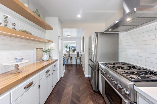 kitchen with backsplash, white cabinetry, ventilation hood, and high end stove