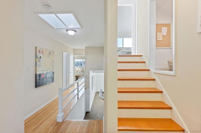 stairs featuring a skylight and hardwood / wood-style floors