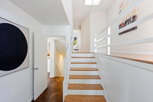 staircase with a skylight and parquet floors