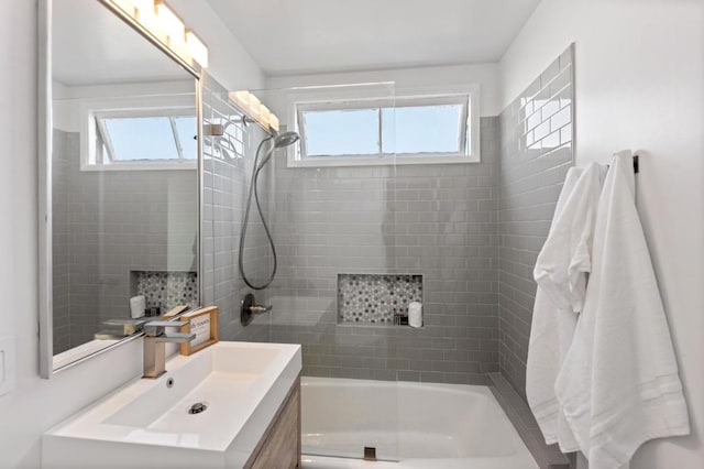 bathroom featuring a wealth of natural light, tiled shower / bath, and vanity