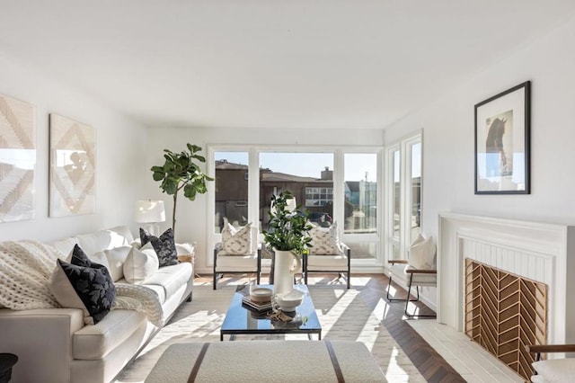 living room featuring a brick fireplace, a wealth of natural light, and light hardwood / wood-style flooring