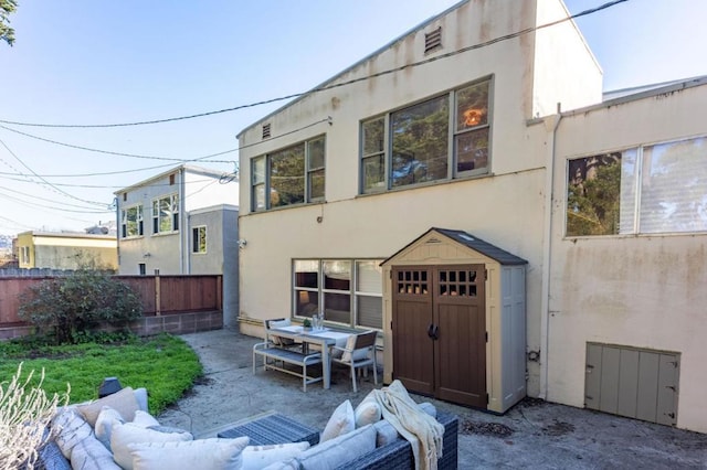 back of property with an outdoor living space, a storage unit, and a patio