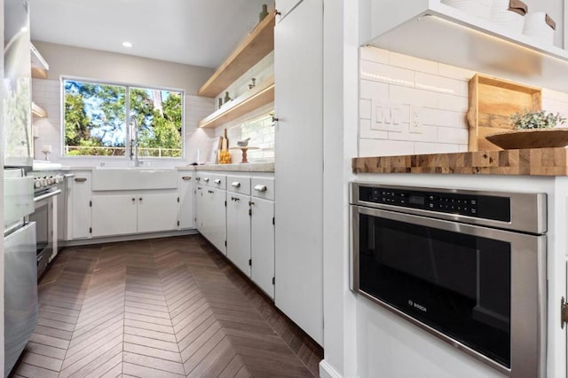 kitchen with white cabinets, stainless steel range oven, sink, backsplash, and wall oven