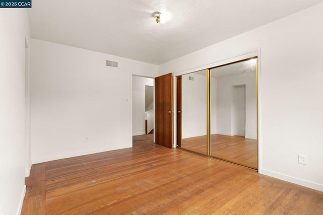 unfurnished bedroom featuring wood-type flooring and a closet