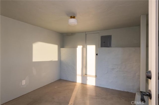 unfurnished room featuring electric panel and concrete floors