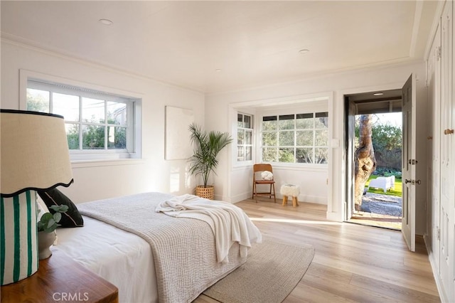 bedroom with light wood-type flooring, access to outside, and ornamental molding