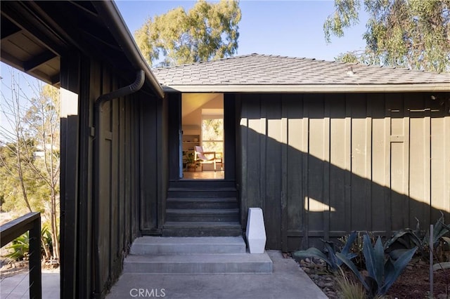 doorway to property with a shingled roof and board and batten siding