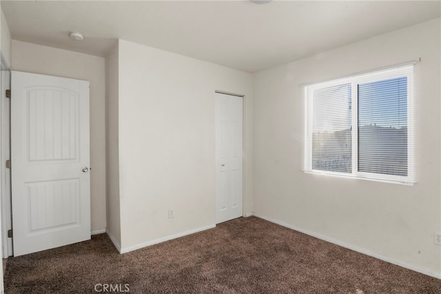 unfurnished bedroom featuring a closet and dark colored carpet