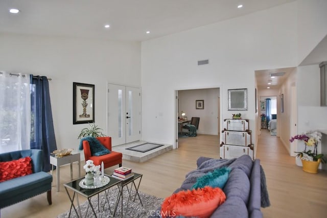 living room featuring french doors, a high ceiling, and light hardwood / wood-style floors