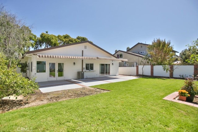 back of property with a patio area, central air condition unit, french doors, and a yard