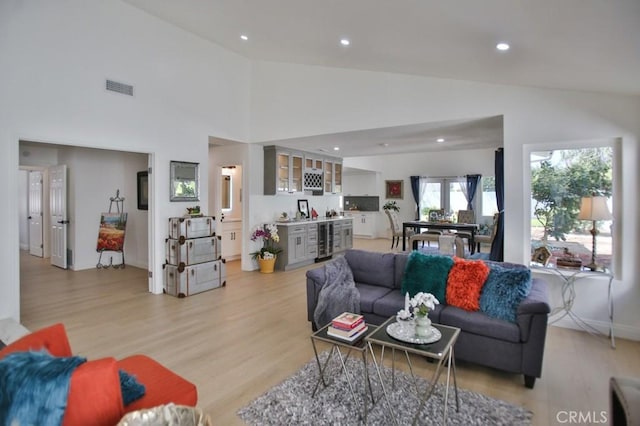 living room featuring high vaulted ceiling, beverage cooler, and light wood-type flooring