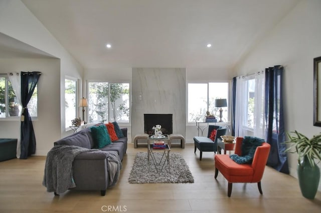 living room featuring vaulted ceiling, light hardwood / wood-style floors, and a fireplace