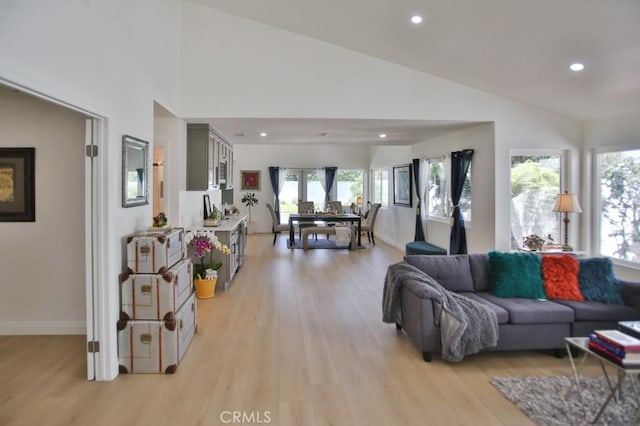 living room with high vaulted ceiling, light wood-type flooring, and a wealth of natural light