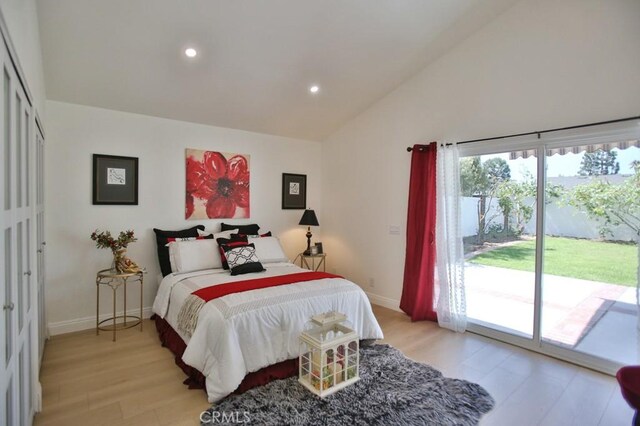 bedroom featuring vaulted ceiling, access to exterior, and light hardwood / wood-style floors